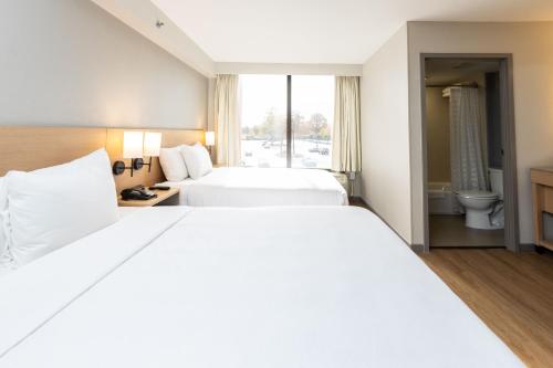 a hotel room with two beds and a bathroom at Hyatt Place Charlotte Arrowood in Charlotte
