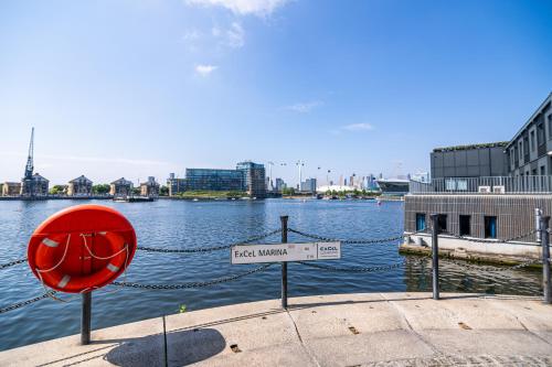 a red sign in front of a body of water at Spacious Excel London Apartment with Balcony, River View and Parking Sleeps 8 in London