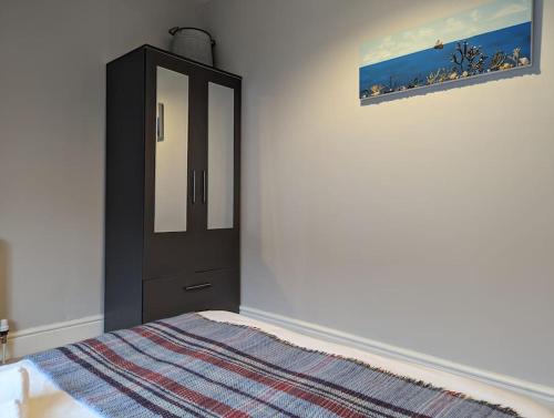 a bedroom with a black cabinet and a bed at Pencartref Apartment - 4 Bedrooms, 3 Bathrooms, Sleeps 7-8 in Aberdyfi