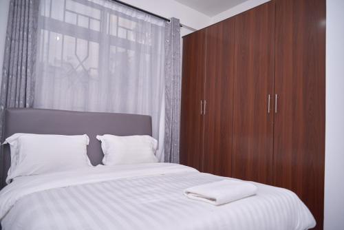 1 dormitorio con 1 cama grande y armario de madera en Diamond Apartments, en Arusha