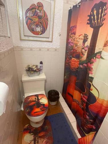 a bathroom with a toilet with a colorful shower curtain at Casa Villas Suizas I cerca de Laberinto de Albania in Apaneca