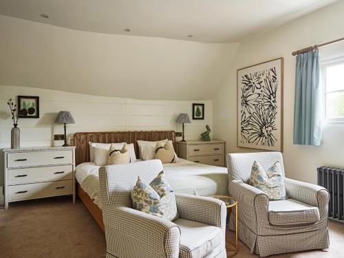 a bedroom with a bed and two wicker chairs at The Old Coach House in Henley on Thames