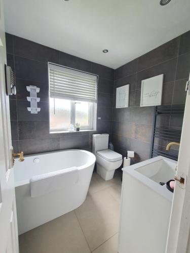 a bathroom with a white tub and a toilet at Professional Stay Doctors Nurses Trades in Luton