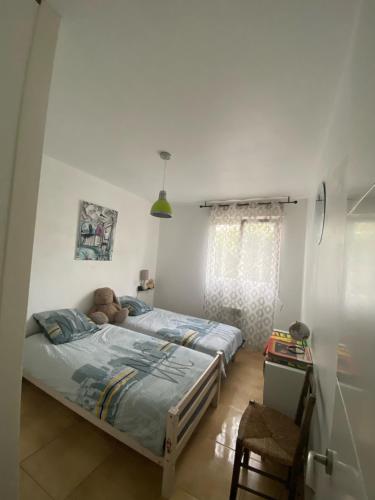 deux lits dans une chambre avec un ours en peluche allongé dessus dans l'établissement Terre et mer, à Urrugne