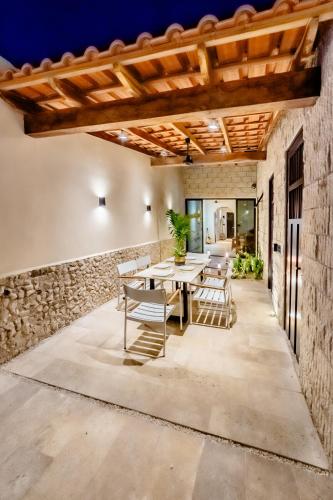 a patio with a table and chairs and a stone wall at Casa mi Merida Centro, alberca, tina, cuarto king size, cuarto 2 camas dobles in Mérida