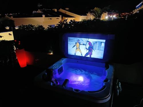 ein Fernseher, der nachts auf einem Whirlpool steht in der Unterkunft Luxury House with sea view, hottub & pool in San Bartolomé de Tirajana