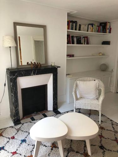 - un salon avec une cheminée, une chaise et un miroir dans l'établissement Appartement Cosy - Abbesses Montmartre, à Paris
