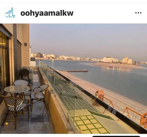 uma varanda com mesas e cadeiras e vista para a água em منتجع اووه يامال البحري في الخيران OOh Yaa Mal em Al Khiran