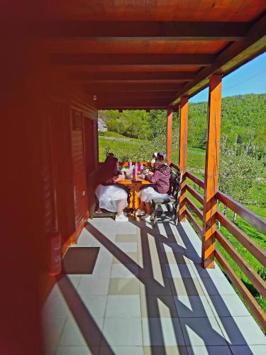 two people sitting at a table on a porch at Ethno village & resort Ćorić in Mojkovac