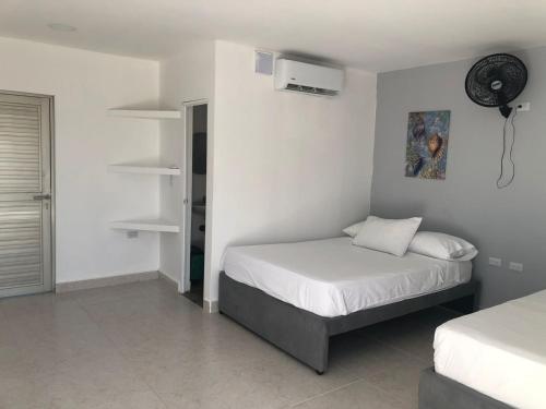 a bedroom with two beds and a fan on the wall at Manglearena in Tolú