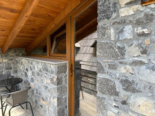 a stone building with a wooden ceiling and a patio at Bujtina Carku in Theth