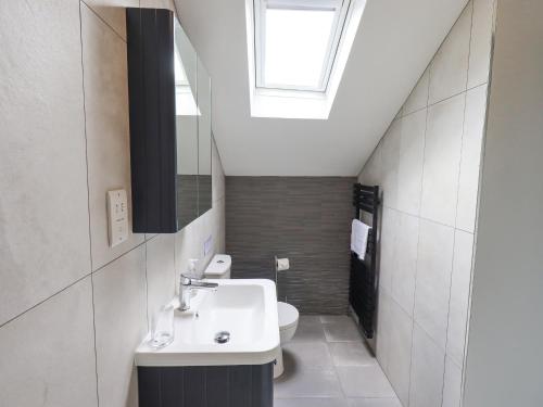 een badkamer met een wastafel en een dakraam bij The Smithy in Borrowdale Valley