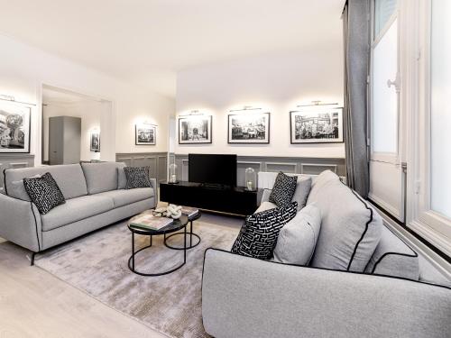 un salon avec deux canapés et une télévision dans l'établissement LivinParis - Luxury AC 4 Bedrooms Auteuil Eiffel, à Paris