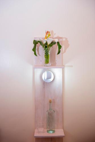 a vase with flowers and a bottle on a shelf at Little Birds Paradise in Ruhengeri
