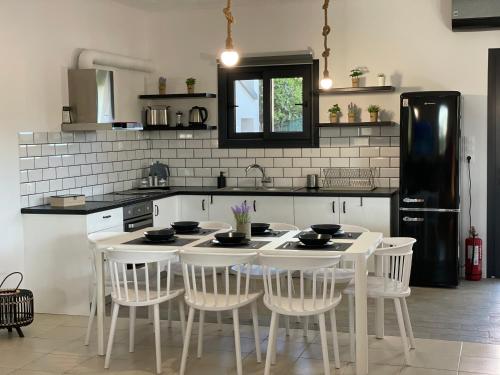 a kitchen with a white table and white chairs at Casa Posidonia in Korinthos