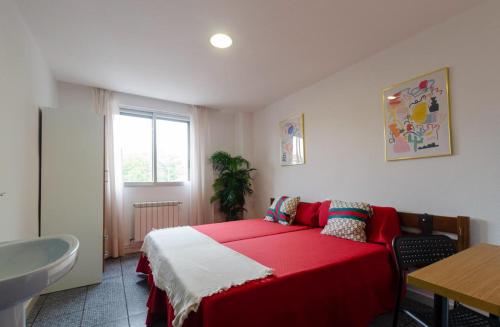 a bedroom with a red bed and a sink at Hostal El Pozarron in Las Rozas de Madrid