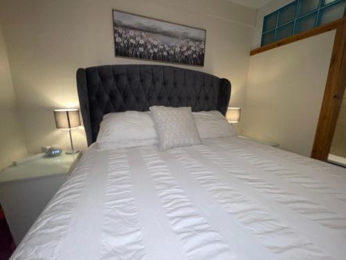 a large bed with a black headboard in a bedroom at Zip Cottage Sleeps 2-3 climb snowdon zip world in Tanygrisiau