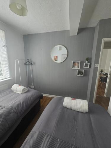 a bedroom with two beds and a mirror on the wall at St Albans City Stays - Near Luton Airport - St Albans Abbey & City Train station - Close to London- Harry Potter World - The Odyssey Cinema - Abbey Cathedral- Contractors I Business I Leisure- sleeps upto 6 people in Saint Albans