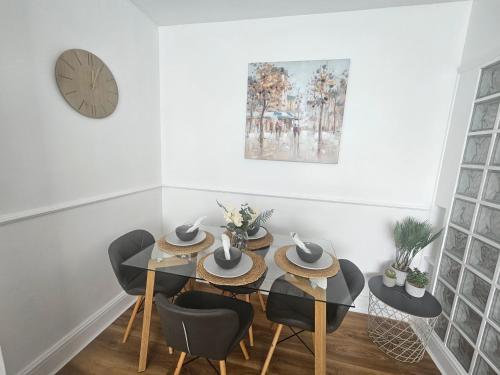 a dining room with a table and chairs and a clock at St Albans City Stays - Near Luton Airport - St Albans Abbey & City Train station - Close to London- Harry Potter World - The Odyssey Cinema - Abbey Cathedral- Contractors I Business I Leisure- sleeps upto 6 people in St. Albans