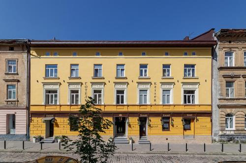 un bâtiment jaune avec des fenêtres blanches sur une rue dans l'établissement Готель Кайзер у Львові, à Lviv