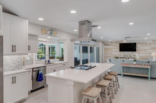 a kitchen with white cabinets and a large island with stools at Casa Del Mar- Stunning Villa with Pool and Spa in Sanibel