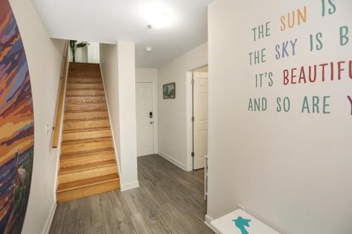 a hallway with a staircase and a wall with a sign on it at Good Day Sunshine by Pristine Properties Vacation Rentals in Mexico Beach
