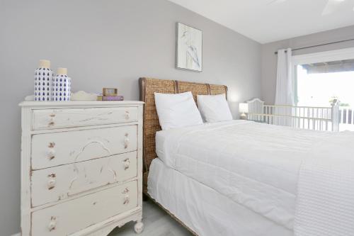 a bedroom with a white bed and a dresser at Pearly Shells by Pristine Properties Vacation Rentals in Saint Joe Beach