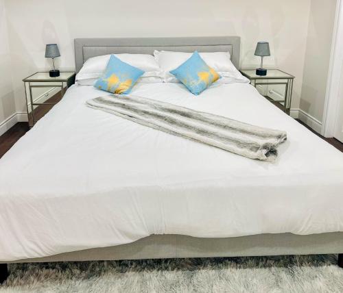 a white bed with blue pillows on it at Spacious 2 Bedroom 1 bath Mississauga Basement Apartment in Mississauga
