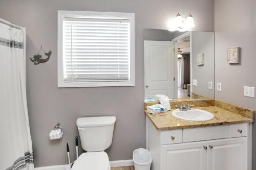 a bathroom with a toilet and a sink and a mirror at Pearly Shells by Pristine Properties Vacation Rentals in Saint Joe Beach