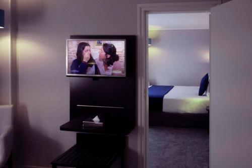 パリにあるベスト ウェスタン アレグロ ネーションのテレビ、ベッドが備わるホテルルームです。