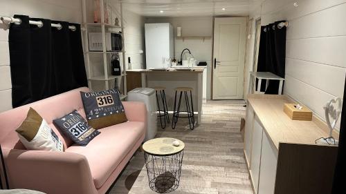 un salon avec un canapé rose et une cuisine dans l'établissement Duo indépendant, piscine et jacuzzi Espace pour vos toutous, à Vidauban