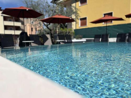 una piscina con ombrelloni, tavoli e sedie di Hotel Al Caminetto WorldHotels Crafted Adults Only a Torri del Benaco