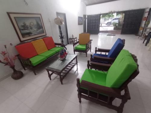 a living room with colorful chairs and a table at CABAÑA LA HERRADURA LUZ ANGELA in Dibulla