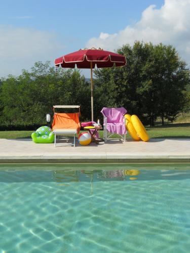 a pool with chairs and an umbrella next to a swimming pool at La Scuola Di Furio Apartments in Fucecchio