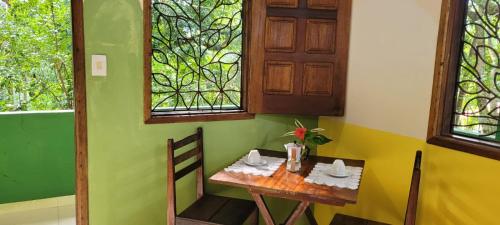 Una pequeña mesa en una habitación con paredes y ventanas verdes. en Pousada Anjali, en Isla de Boipeba