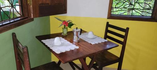 una mesa de madera con 2 sillas y un jarrón de flores en Pousada Anjali, en Isla de Boipeba