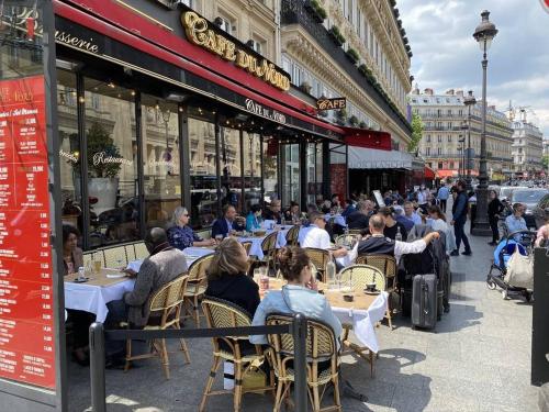 un groupe de personnes assises à des tables à l'extérieur d'un restaurant dans l'établissement Studio Parisien individuel - GN, à Paris