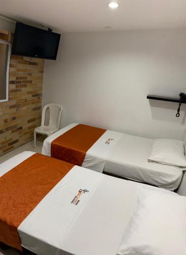 a hotel room with two beds and a chair at Hotel San Lorenzo in Bucaramanga