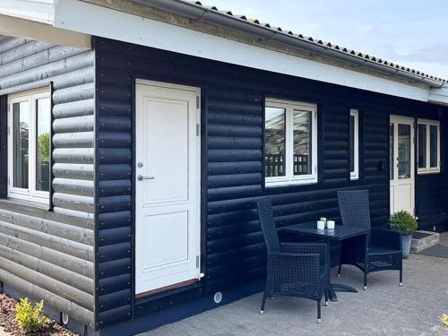 una pequeña casa negra con mesa y sillas en 4 person holiday home in Faaborg en Bøjden