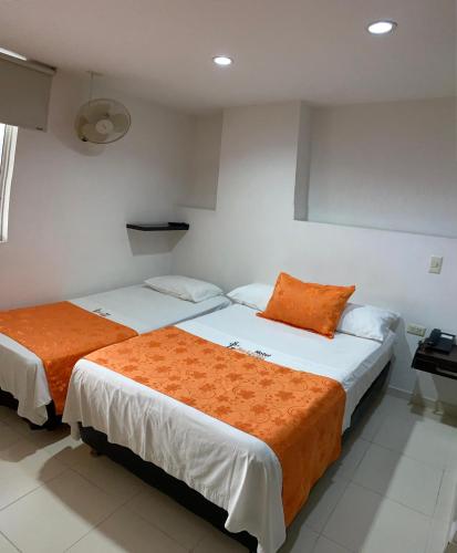 two beds in a room with white walls and orange pillows at Hotel San Lorenzo in Bucaramanga