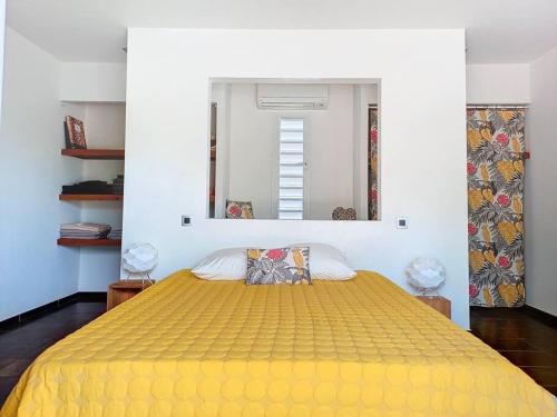 ein Schlafzimmer mit einem gelben Bett und einem Spiegel in der Unterkunft Villa vue mer et montagne Pelée in Le Carbet