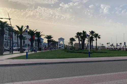 The heart of M'diq! 4 min from beach في المضيق: شارع مليء بأشجار النخيل وحديقة بها برج ساعة