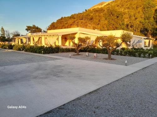 a yellow building with trees in front of a mountain at Teia Holiday Apartments in Vulcano