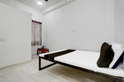 een slaapkamer met een bed met witte lakens en zwarte kussens bij SPOT ON Khandekar Lodge and Restaurant in Nagpur