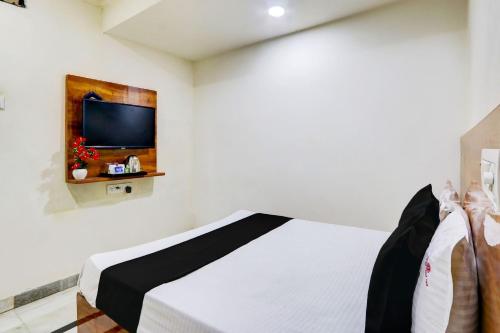 1 dormitorio con 1 cama y TV en la pared en OYO Hotel New Hitech Inn, en Hyderabad