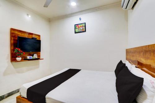 1 dormitorio con 1 cama y TV en la pared en OYO Hotel New Hitech Inn, en Hyderabad