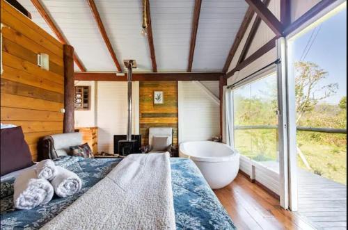 a bedroom with a large bed and a bath tub at Chalés Altos da Serra - Chalé Pinhão em Urubici SC in Urubici