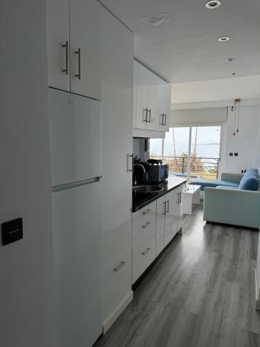 a white kitchen with white cabinets and a couch at Paraíso sobre el Mar Torremolinos Santa Clara in Torremolinos