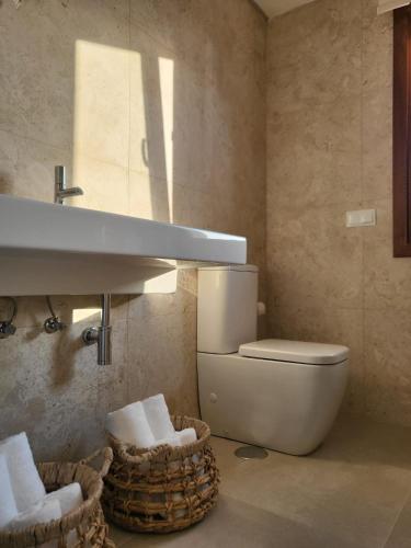 a bathroom with a toilet and a sink and baskets at Limens Luxury Apartment in Cangas de Morrazo