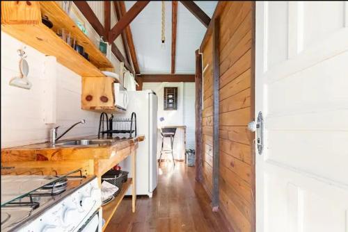 a kitchen with a sink and a white refrigerator at Chalés Altos da Serra - Chalé Pinhão em Urubici SC in Urubici